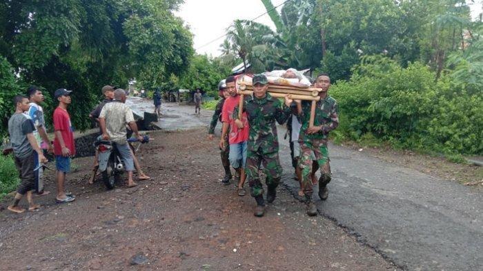 TNI dan warga menggotong seorang warga yang jadi korban banjir di wilayah Ile Ape, Kabupaten Lembata, Minggu 4 April 2021.