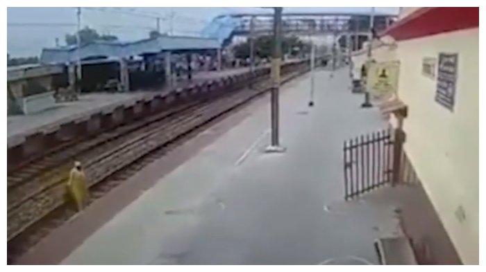 Seorang wanita lebih memilih menyeberangi perlintasan kereta api dari pada menggunakan jembatan penyeberangan.