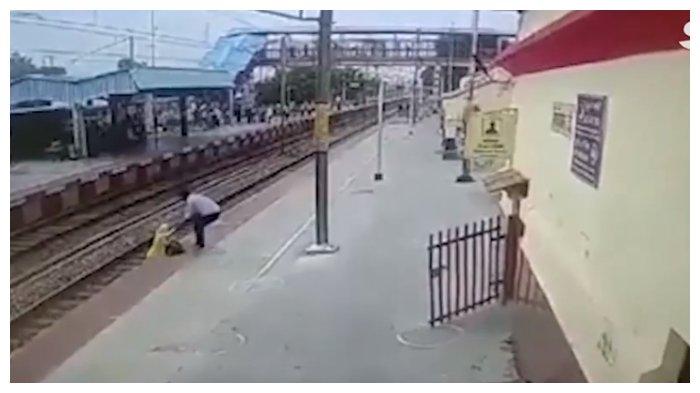 Seorang petugas stasiun berlair dan menolong wanita yang kesulitan memanjat peron