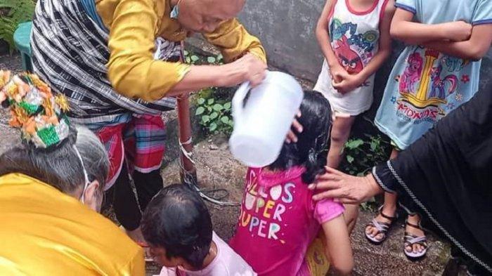 Seorang tetua adat di Kelurahan Kadolomoko, Kota Baubau, Sulawesi Tenggara, tengah memandikan anak yatimpiatu, Kamis (19/8/2021). Ritual memulai Pekansena Anaana Maelu.