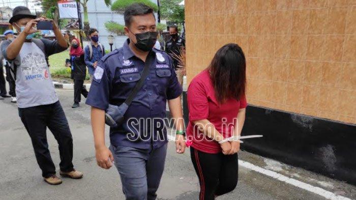 BY, muncikari prostitusi online menutupi wajahnya dengan rambut saat digiring polisi ke sel tahanan Polres Blitar Kota, Rabu (7/4/2021).