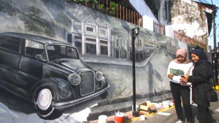 Warga melintasi mural pertokoan Kayutangan di Kampoeng Heritage Kajoe Tangan, Kota Malang.