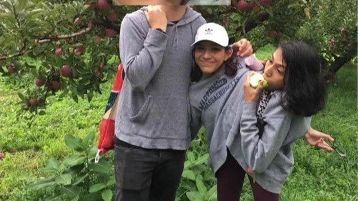 Lupita sedang menikmati apel saat saudara kembarnya berfoto