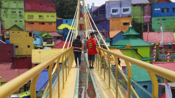 Sejumlah wisatawan saat melintas di jembatan kaca yang menghubungkan Kampung Warna - warni dan Kampung Tridi di Kota Malang, Jawa Timur, Selasa (10/10/2017).