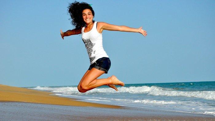 Pengunjung wanita yang sedang menikmati liburan ke pantai