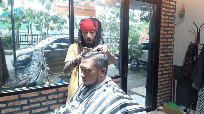 CUKUR RAMBUT - Diding yang berpenampilan seperti Jack Sparrow saat mencukur rambut konsumennya di Jack Dink's Barbershop & Dreadlock, Jalan Perjuangan, Kota Cirebon, Sabtu (6/3/2021)
