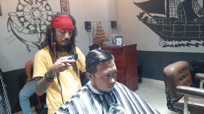 CUKUR RAMBUT - Diding yang berpenampilan seperti Jack Sparrow saat mencukur rambut konsumennya di Jack Dink's Barbershop & Dreadlock, Jalan Perjuangan, Kota Cirebon, Sabtu (6/3/2021)