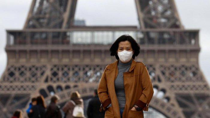 Ilustrasi, seorang perempuan memakai masker pelindung saat penularan virus korona di lapangan terbuka Trocadero di depan Menara Eiffel di Paris, Prancis.