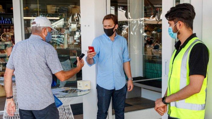 Paspor vaksin pelanggan diperiksa saat mereka masuk untuk makan di sebuah restoran di Auckland pada 3 Desember 2021.
