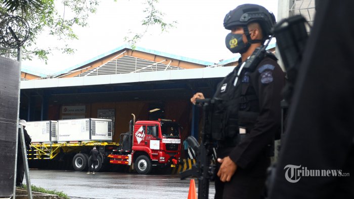 Pekerja dengan penjagaan petugas kepolisian melakukan bongkar muat Envirotainer berisi vaksin COVID-19 Sinovac setibanya dari Beijing di Terminal Cargo Bandara Soekarno Hatta, Tangerang, Banten, Kamis (31/12/2020). Sebanyak 1,8 juta dosis vaksin COVID-19 Sinovac kembali tiba di Indonesia yang selanjutnya dibawa ke Bio Farma Bandung untuk dilakukan uji klinis. TRIBUNNEWS/IRWAN RISMAWAN