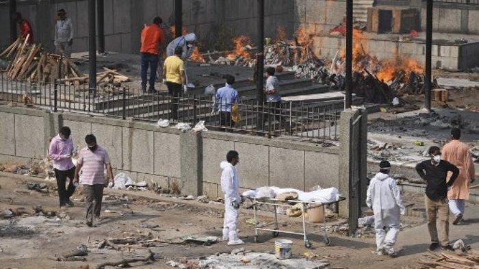 Kerabat yang mengenakan pakaian pelindung diri (APD) berdiri di samping tandu dengan tubuh seseorang yang meninggal karena virus Corona Covid-19, di tempat kremasi di New Delhi pada 2 Mei 2021.