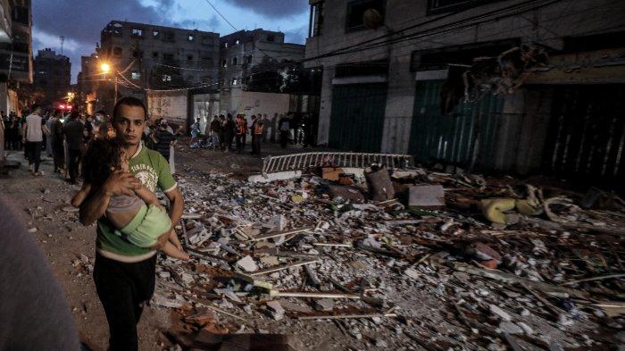 Seorang pria yang menggendong escort setelah pesawat tempur Israel melancarkan serangan di Jalur Gaza.
