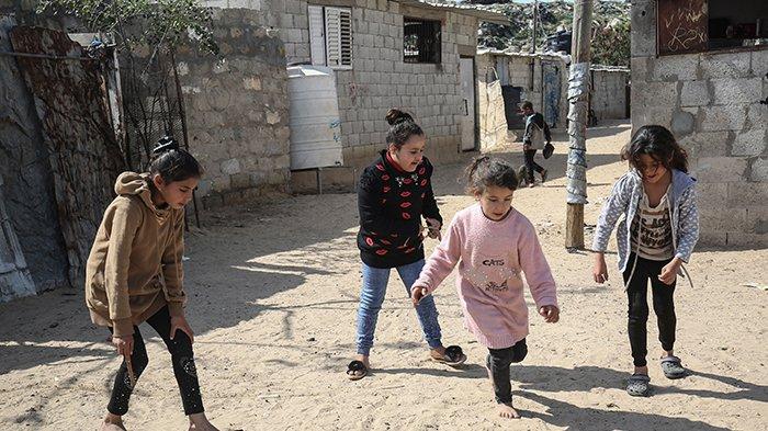 Anak-anak perempuan Palestina di sebuah jalan di kamp Khan Yunis untuk pengungsi Palestina di Jalur Gaza selatan pada 24 Februari 2021. - Saat warga Palestina bersiap untuk pemilihan pertama mereka dalam 15 tahun, dua pemain kuat muncul dari jauh. Salah satunya adalah penasihat kerajaan yang tinggal di Uni Emirat Arab yang kaya yang baru saja mengirimkan pengiriman besar vaksin Covid ke Jalur Gaza yang miskin.