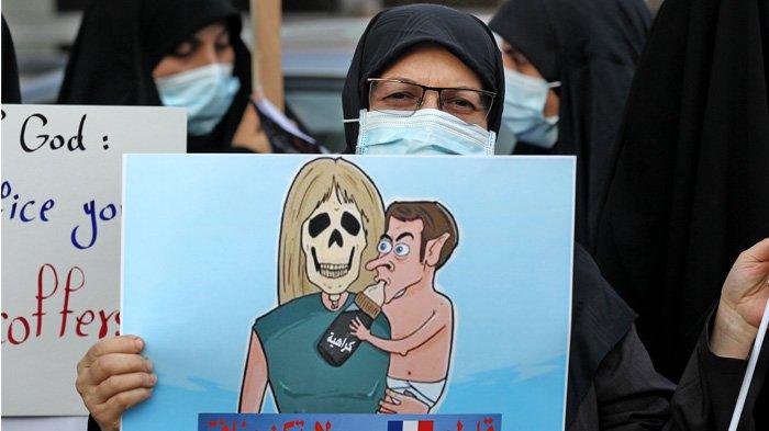 IRAK - Para pengunjuk rasa Irak membawa poster selama demonstrasi menentang Presiden Prancis Emmanuel Macron di depan kedutaan besar Prancis di Baghdad pada 26 Oktober 2020. Seruan untuk memboikot barang-barang Prancis berkembang di dunia Arab dan sekitarnya, setelah Presiden Emmanuel Macron mengkritik kaum Islamis dan bersumpah tidak untuk