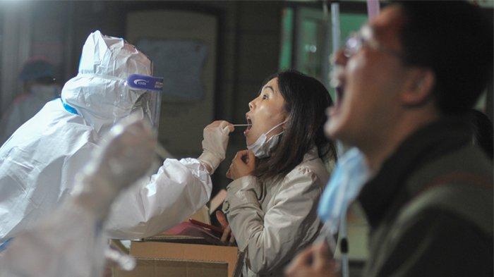 Foto yang diambil pada 13 Oktober 2020 ini menunjukkan seorang petugas kesehatan mengambil sampel dari seorang penduduk untuk dites virus corona COVID-19 sebagai bagian dari program pengujian massal menyusul wabah baru virus korona di Qingdao, di provinsi Shandong timur China. (STR / AFP / China OUT)