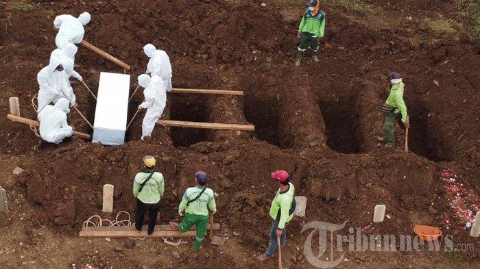 Petugas mengubur jenazah terkait Covid-19 di Taman Pemakaman Umum (TPU) Srengseng Sawah, Jakarta Selatan, Jumat (15/1/2021). Media luar negeri mulai menyoroti penanganan pandemi Covid-19 di Indonesia setelah seorang pasien positif yang ditolak 10 rumah sakit meninggal dunia.