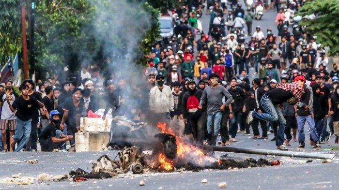 Seorang pemuda melempar batu ke polisi anti huru hara pada hari kedua mogok kerja nasional menolak UU Cipta Kerja di Lampung pada 7 Oktober 2020.