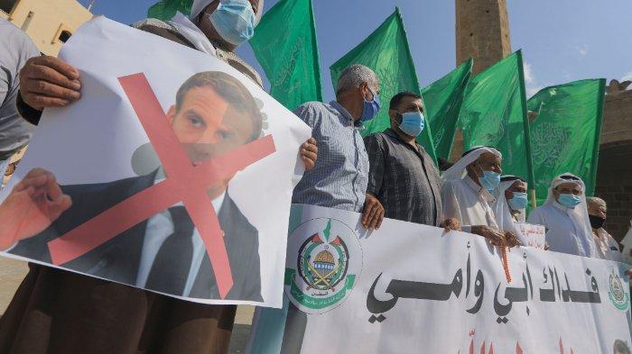 Demonstran Palestina mengangkat bendera dan plakat dalam unjuk rasa memprotes komentar Presiden Prancis Emmanuel Macron atas kartun Nabi Muhammad, di Deir al-Balah di Jalur Gaza tengah, pada 25 Oktober 2020.