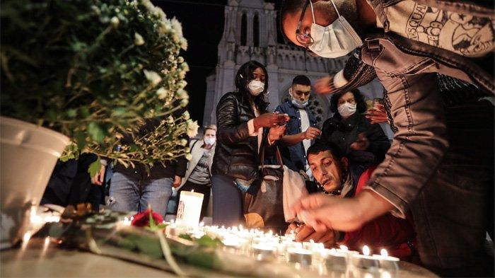 Sejumlah warga menyalakan lilin di luar Basilika Notre-Dame de l'Assomption di Nice pada tanggal 29 Oktober 2020 untuk menghormati tiga korban penyerang pisau, yang memotong tenggorokan setidaknya satu wanita, di dalam gereja di kota French Riviera.