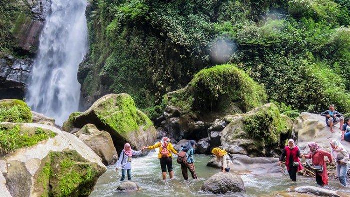 Pengunjung menyeberangi sungai menuju Air Terjun Kedung Kayang.