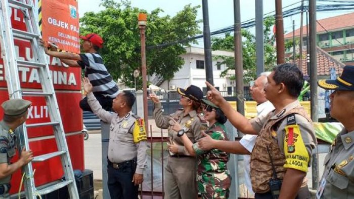 Sejumlah peugas gabungan melakukan pemasangan stiker penunggak pajak reklame di SPBU di Kecamatan Koja, Jakarta Utara, Rabu (24/10).