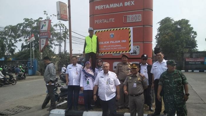 Sejumlah peugas gabungan melakukan pemasangan stiker penunggak pajak reklame di SPBU di Kecamatan Koja, Jakarta Utara, Rabu (24/10).