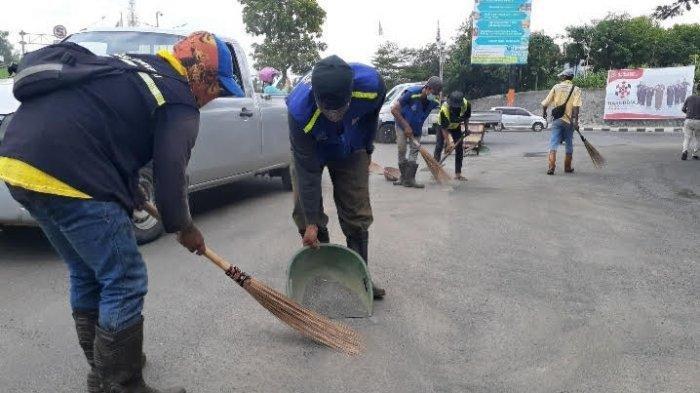 Sejumlah petugas Dinas Pekerjaan Umum membersihkan pasir dan kerikil di Jalan Ciater Raya, Serpong, Jumat (11/12/2020).