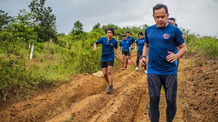 Bima Arya, Wali Kota Bogor sekaligus Ketua Umum Asosiasi Lari Trail Indonesia (ALTI) 2022-2025, lari menyusuri trek alam bersama pelari trail lainnya dalam sebuah event.