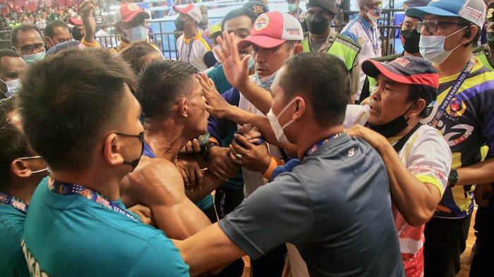 Tim ofisial tinju DKI Jakarta berusaha menenangkan atlet tinjunya, Jill Mandagie (tengah) yang mengamuk di luar ring dampak dari keputusan wasit memenangkan lawannya petinju dari Nusa Tenggara Barat. Jill Mandagie (DKI Jakarta) turun di kelas Bantam (52-56 kg) berhadapan dengan Lucky Mira Agusto Hari (Nusa Tenggara Timur) ajang Tinju PON XX Papua di Gedung Olahraga Cenderawasih, Jayapura, Jumat (8/102021) sore.