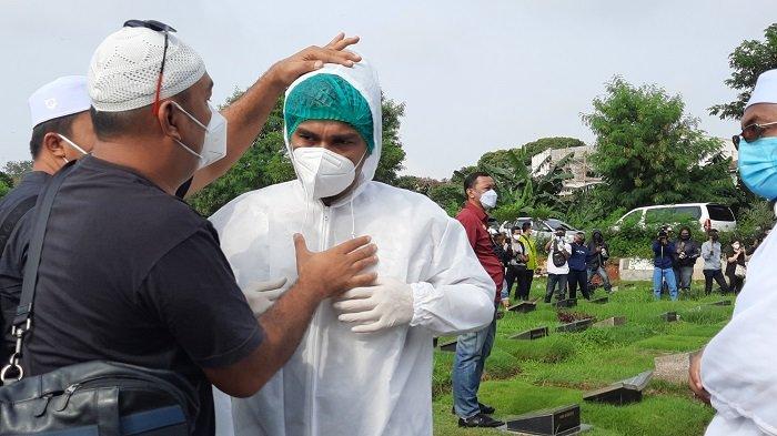 Teddy Syach saat memakai APD saat ikut memakamkan istrinya, Rina Gunawan, di TPU Tanah Kusir Jakarta Selatan, Selasa (3/3/2021).