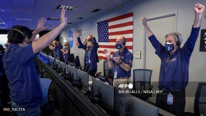Foto NASA ini menunjukkan anggota tim penjelajah Perseverance NASA saat mereka bereaksi dalam kontrol misi setelah menerima konfirmasi bahwa pesawat luar angkasa berhasil mendarat di Mars, pada 18 Februari 2021, di Laboratorium Propulsi Jet NASA di Pasadena, California.